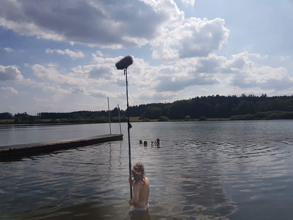 Markus Egloff standing in a lake, holding the boom over swimmers during a shoot